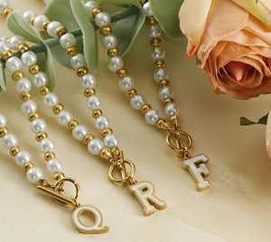 Détail du collier de perles à boucle OT plaqué or 18K avec pendentifs lettres en émail