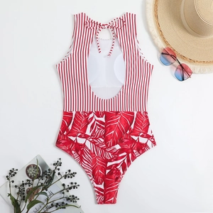 Detail of a red tropical leaf and striped one-piece swimsuit with open back and tie-up