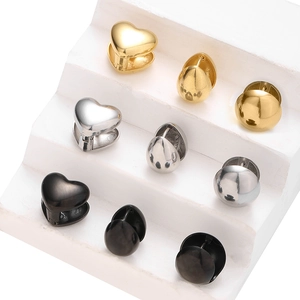 Macro detail of stainless steel heart, drop, and round huggie earrings in gold, silver, and black