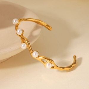 Dettaglio del bracciale rigido dorato ondulato in acciaio inossidabile con cinque perle