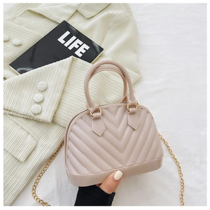 Detail of pink shell-shaped jelly bag featuring elegant V-pattern and gold metal chain