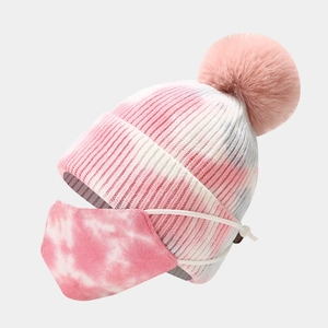Dettaglio del berretto in maglia tie-dye rosa con pompon e maschera coordinata per l'inverno