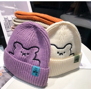 Detail of cute bear embroidery and smile patch on soft knitted beanies in multi colors