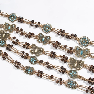 Detail of bohemian braided waist belt with wooden beads and butterfly rhinestone buckle