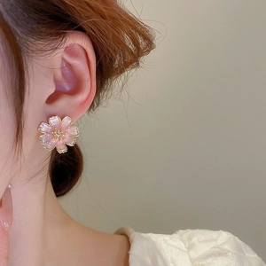 Detail of pink gradient flower earring worn on ear with elegant golden trim accents