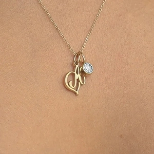 Close-up of gold stainless steel necklace with letter M and clear round crystal birthstone