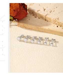 Detailed view of silver heart studs with 925 hallmark on a textured surface