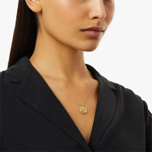 Close-up of gold coin necklace featuring nature elements engraving on a female model