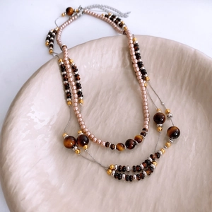 Close-up of vintage tiger eye and pearl beaded necklace with metallic lobster clasp