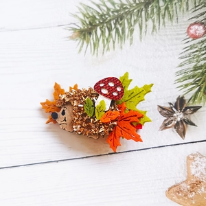 Detailed view of handmade hedgehog hair clip with felt autumn maple leaves and mushroom
