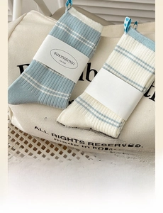 Detail of cream blue striped cotton socks with heart label on canvas bag background