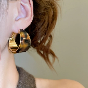 Gros plan de boucles d'oreilles C en résine écaille de tortue avec doublure en métal doré 18K