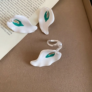 Detailed view of Calla Lily jewelry set with white enamel and green accents on leather