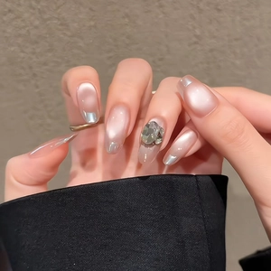 Detail of nude gradient press-on nails with silver French tips and a large rhinestone