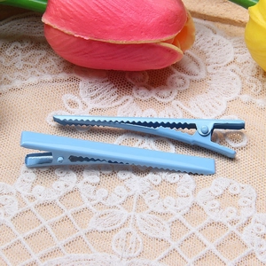 Detail of light blue duckbill hair clips with non-slip serrated edges on lace
