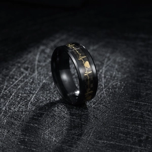 Macro shot of 8mm black titanium ring with gold heartbeat line and carbon fiber inlay