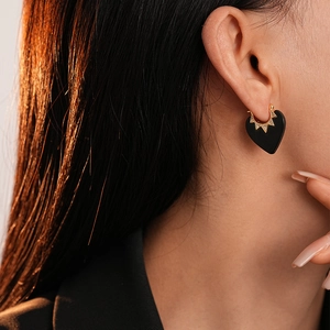 Gros plan détaillé de boucles d'oreilles cœur noir avec émail et zircons sur un modèle