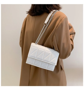 Detailed shot of a white quilted crossbody bag with silver chain strap on a model