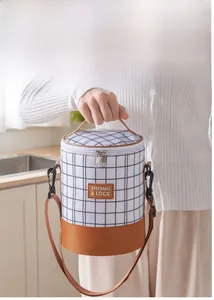 Detail of checkered cylindrical lunch bag with leather base and adjustable strap