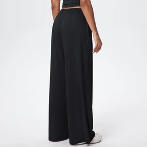Detail of high-waist black wide-leg trousers with elastic drawstring and draped fabric