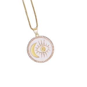 Close-up of golden zircon moon and evil eye pendant with white enamel detail