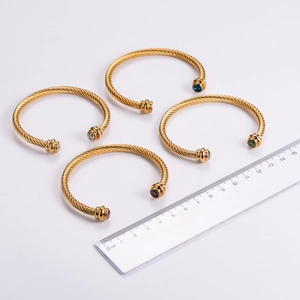 Détail de quatre bracelets câblés dorés ornés de pierres précieuses multicolores