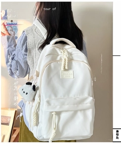 Close-up of a white minimalist backpack featuring a panda plush charm and side profile