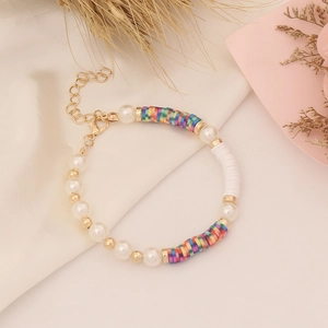 Detail of bohemian bracelet with white pearls, colored clay beads and golden clasp closure