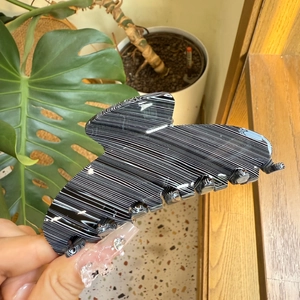 Detailed macro view of large black and white striped acetate hair claw clip held by hand