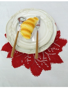 Close-up of red Christmas lace placemat with elegant embossed ceramic plates