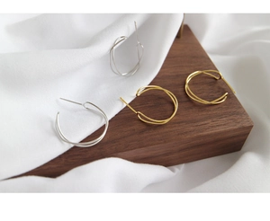 Close-up of intertwining wave earrings in silver and gold finish on elegant background