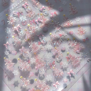 Sparkly Christmas nail stickers with 3D pink bows, trees and snowflakes in soft sunlight
