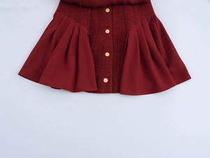 Detail view of burgundy tweed skirt featuring golden buttons and pleated side panels