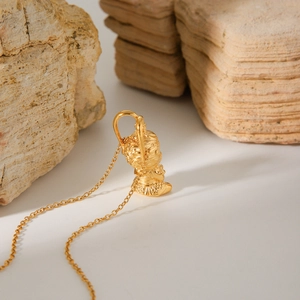 3D Monkey King pendant necklace in 18K gold-plated stainless steel on a rock stand