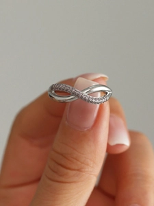 Close-up of silver infinity ring featuring delicate pink cubic zirconia pave setting