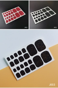 Macro shot of glittery red and black toe nail polish wraps in different sizes