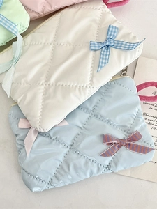 Quilted bow makeup bag in soft pastel colors with a textured finish and top handle