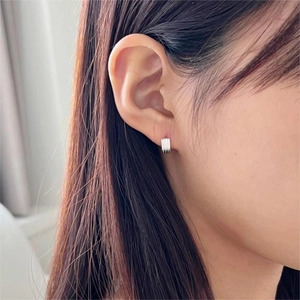 Macro detail of silver minimalist striped hoop earrings on a model's ear lobe