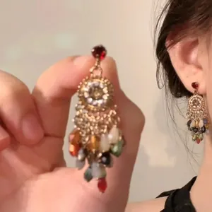 Detail of vintage bohemian drop earrings featuring colorful teardrop beads and gold alloy