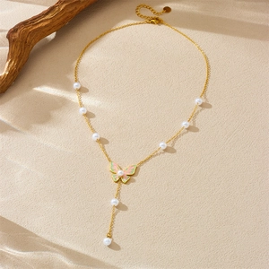 Y-shaped necklace with colorful butterfly pendant and pearl drop on sandy background