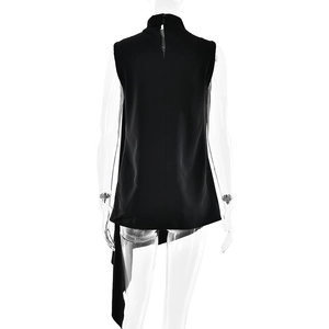 Detail view of the black sleeveless top featuring a mock neck and asymmetrical back hemline