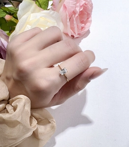 Detailed view of emerald-cut moissanite ring in gold plating on elegant floral background