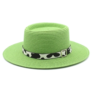 Detail of green straw boater hat with cow print band and silver metal buckle