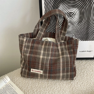 Detail of vintage plaid tote bag with retro tweed texture and brand logo patch
