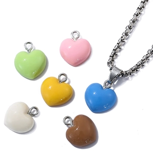 Flat lay of colorful resin heart pendants with silver chain on white background