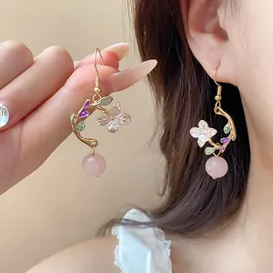 Dettaglio di orecchini a fiore vintage con nappe in conchiglia e perle rosa sul modello