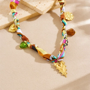 Detail of printed silk scarf necklace with golden heart charms and amber beads