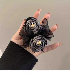 Detailed close-up of dark grey fabric flower hair claw with black lace mesh ribbon bow