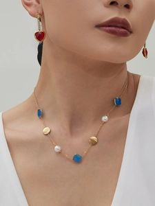 Detail der 18k vergoldeten Halskette mit blauen Steinen und roten Herzohrringen