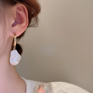 Dettaglio degli orecchini a cuore con perle irregolari e finitura cangiante su modella